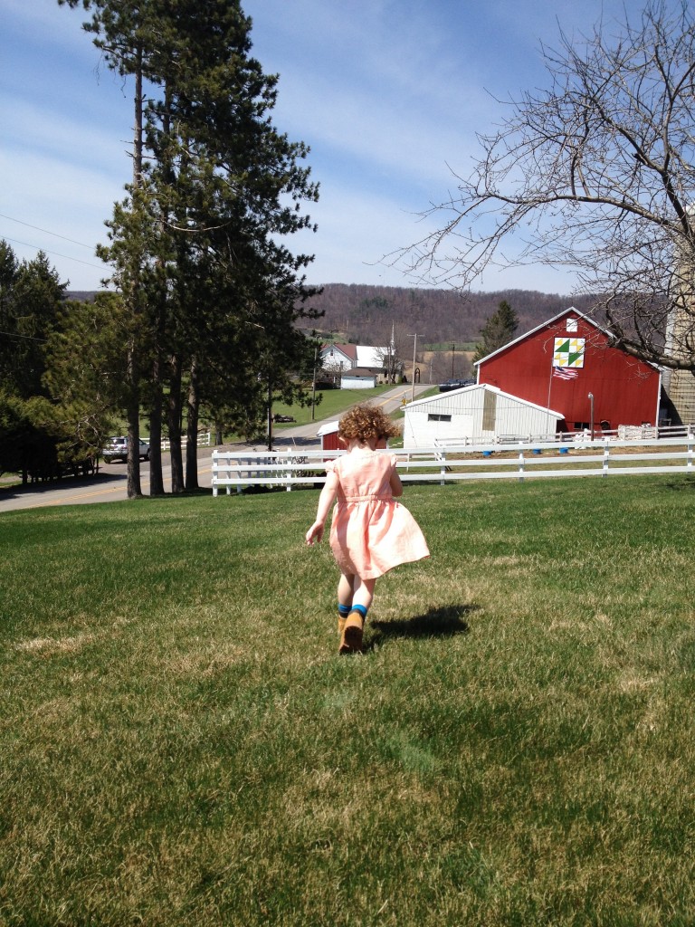 Girl running toward red barn